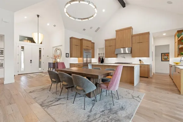 a dining hall with stainless steel appliances kitchen island granite countertop a table chairs and a refrigerator