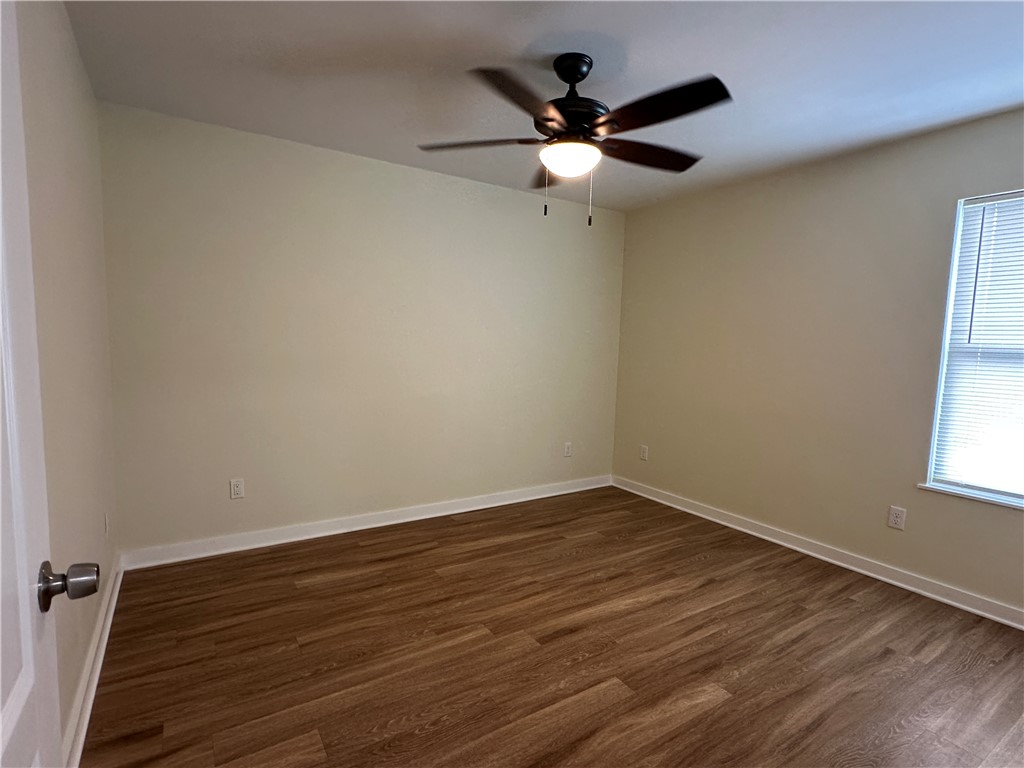923 Craig Street, Unit B Corpus Christi, TX 78404 - Photo 5 of 9 an empty room with wooden floor fan and windows
