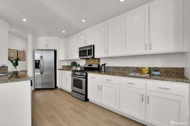 a kitchen with granite countertop white cabinets and stainless steel appliances