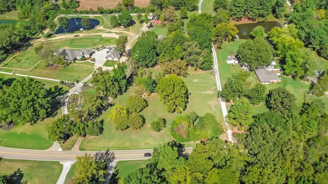 an aerial view of residential houses with outdoor space and trees all around