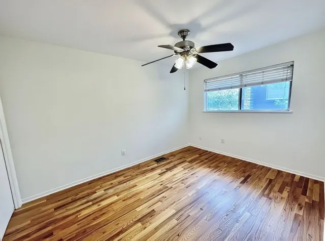 a view of a room with wooden floor closet and a ceiling fan
