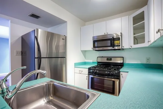 a kitchen with stainless steel appliances wooden cabinets a stove and a microwave
