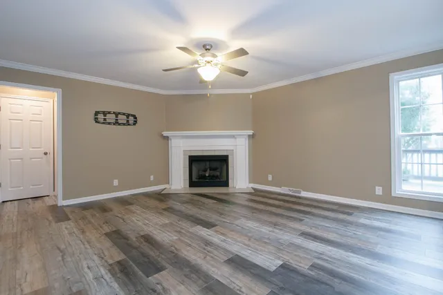 an empty room with wooden floor fan and windows