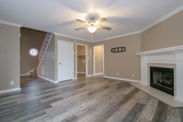 a view of an empty room with wooden floor fireplace and a window