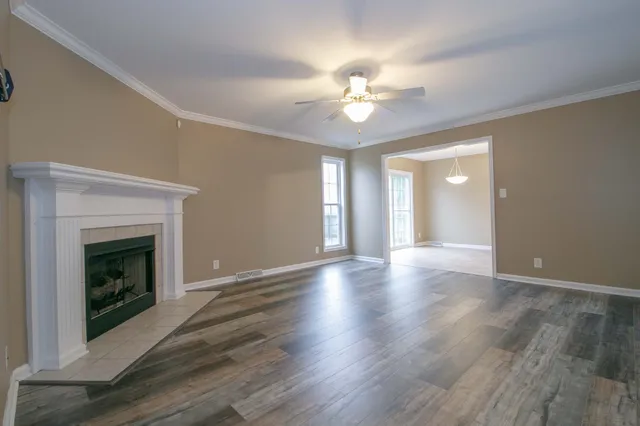 a view of an empty room with wooden floor and fireplace
