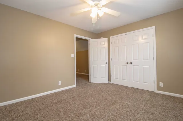 an empty room with a chandelier fan and closet area