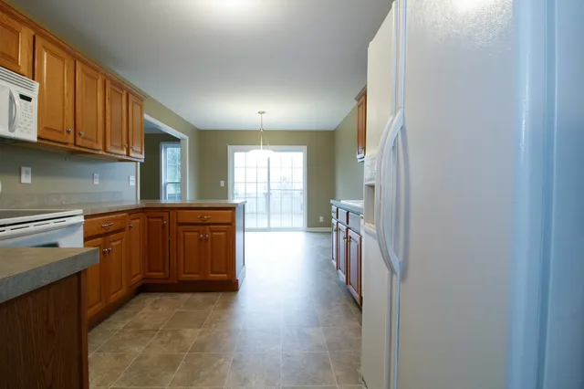 a kitchen with stainless steel appliances granite countertop a refrigerator a sink dishwasher and wooden cabinets with wooden floor