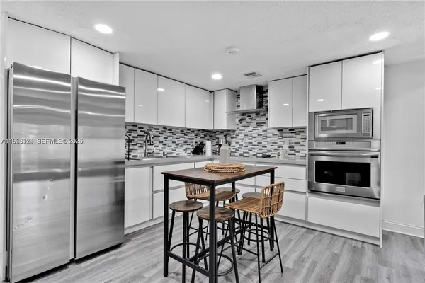 a kitchen with stainless steel appliances kitchen island granite countertop a refrigerator a stove a microwave oven with a dining table and chairs