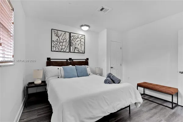 a bedroom with bed and a painting on the wall