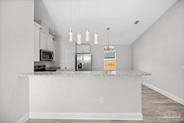 a view of a kitchen with center island and stainless steel appliances