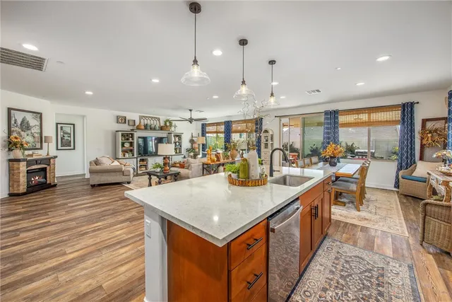 a kitchen with stainless steel appliances granite countertop a stove top oven a refrigerator a sink and a dining table with wooden floor