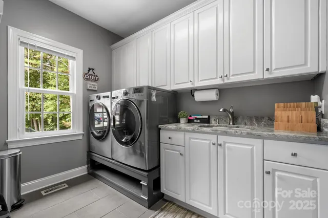 a utility room with stainless steel appliances granite countertop a sink and a window
