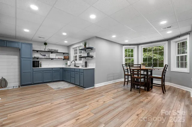 a kitchen with stainless steel appliances kitchen island granite countertop a table chairs sink and cabinets