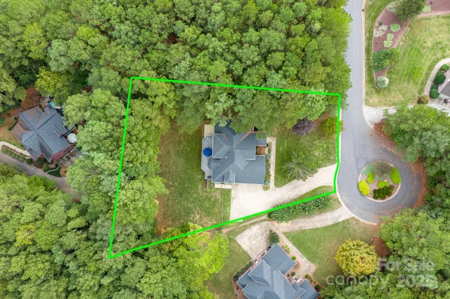 an aerial view of a house with a yard and trees all around