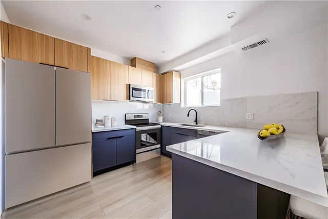 a kitchen with a refrigerator a stove a sink a center island and wooden floor