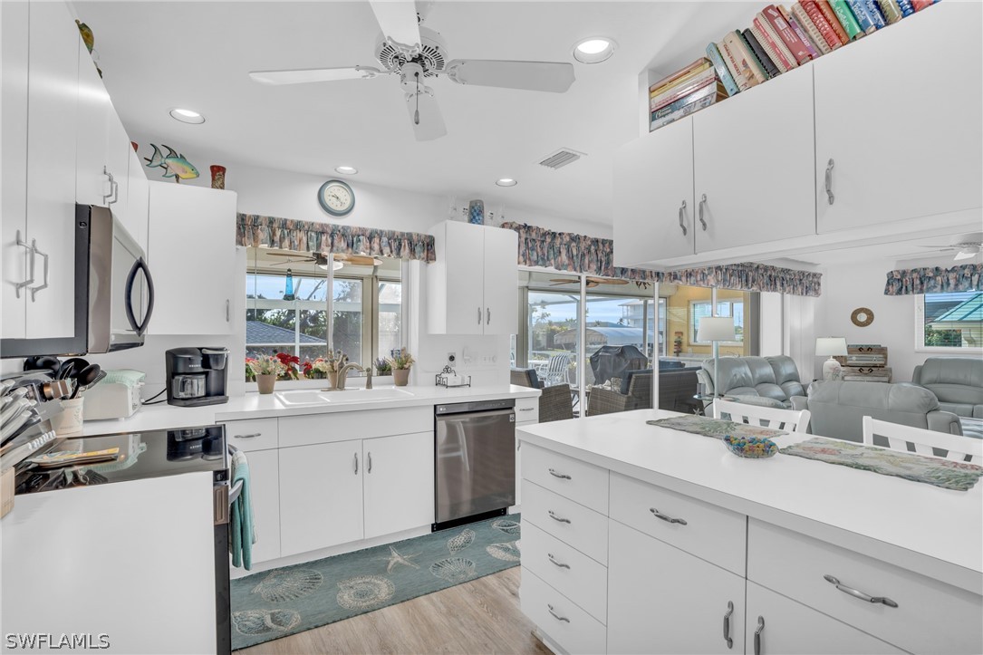 3278 York Road St. James City, FL 33956 - Photo 19 of 49 a kitchen with stainless steel appliances kitchen island granite countertop a sink dishwasher and white cabinets with wooden floor