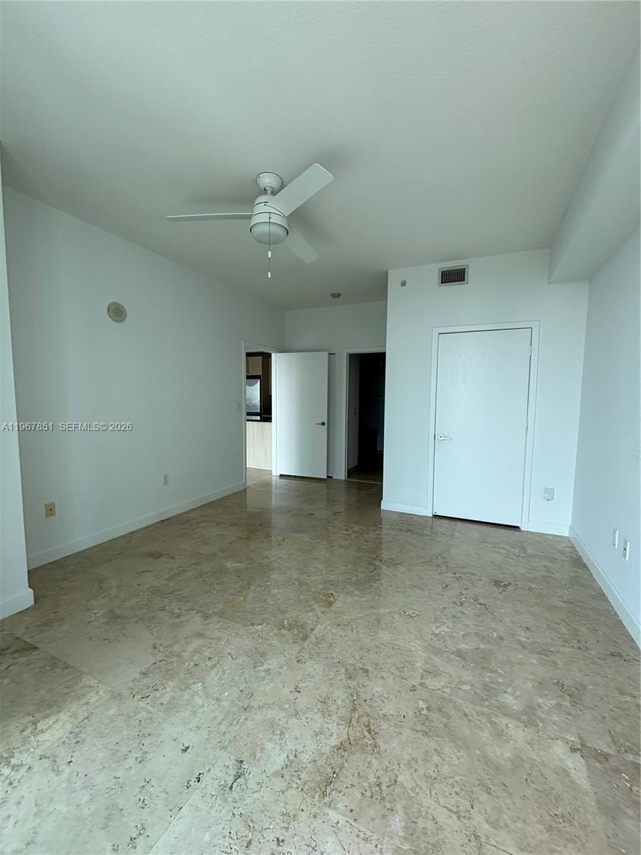 79 Southwest 12th Street, Unit 2703S Miami, FL 33130 - Photo 15 of 61 an empty room with a ceiling fan and carpet