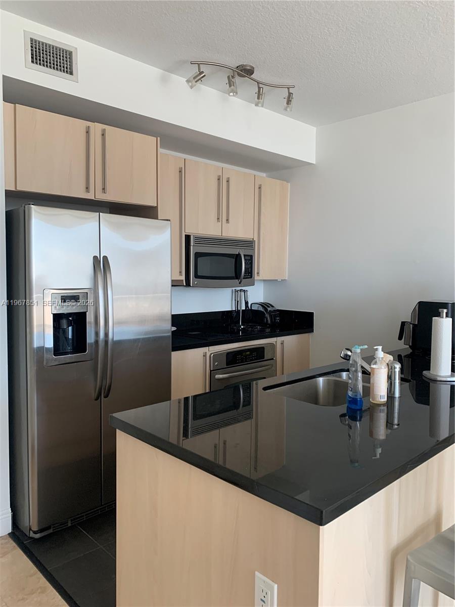 79 Southwest 12th Street, Unit 2703S Miami, FL 33130 - Photo 9 of 61 a kitchen with kitchen island a counter top space cabinets and stainless steel appliances