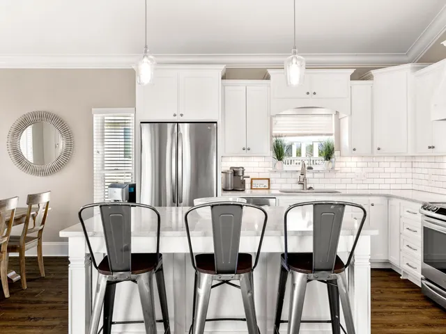a kitchen with stainless steel appliances a dining table chairs a refrigerator and cabinets