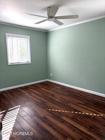 a view of a room with wooden floor a ceiling fan and windows