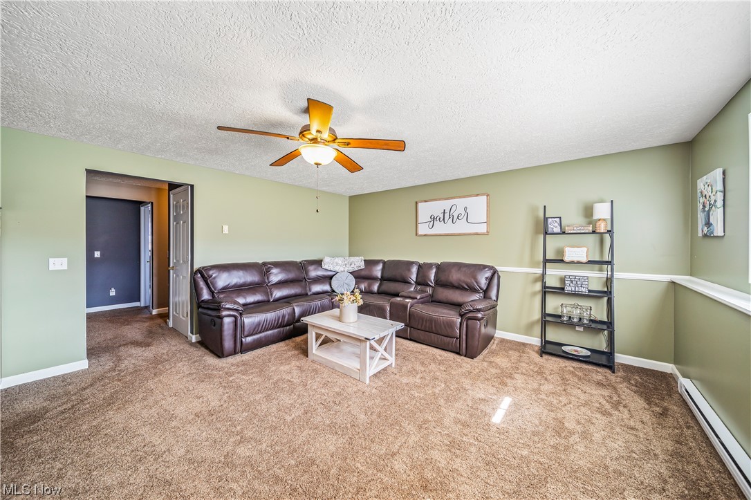 7290 Turner Road Pierpont, OH 44082 - Photo 20 of 36 Living room with carpet floors, baseboard heating, a textured ceiling, and ceiling fan