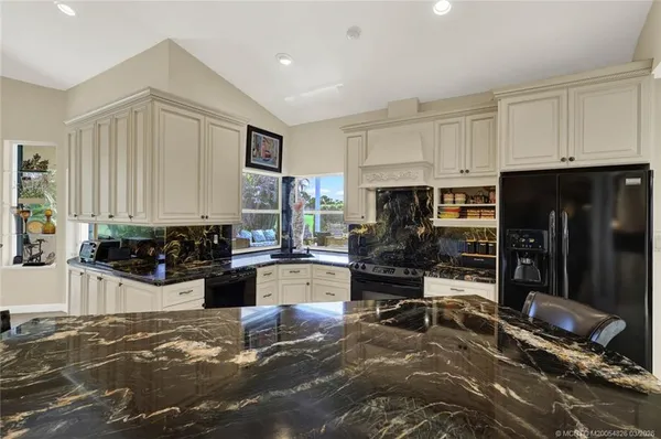 a dining room with stainless steel appliances kitchen island granite countertop a dining table chairs and a refrigerator