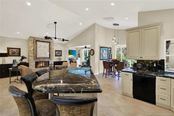 a kitchen with stainless steel appliances a sink a stove a refrigerator cabinets and chairs