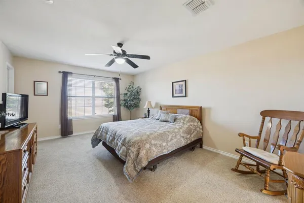 a bedroom with a bed a chair and a flat screen tv