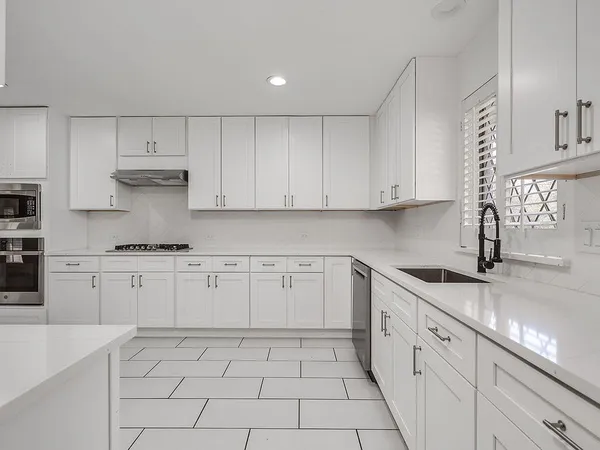 a kitchen with granite countertop white cabinets and white appliances