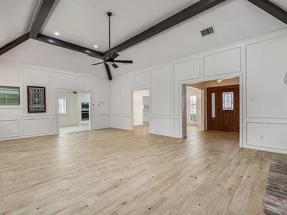a view of empty room with wooden floor and ceiling fan