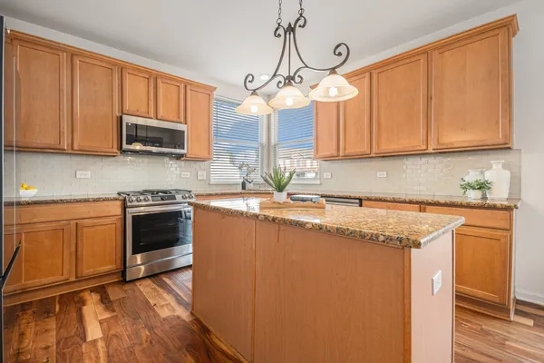 a kitchen with stainless steel appliances granite countertop a sink a stove a microwave and wooden cabinets