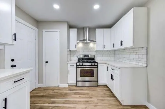 a kitchen with stainless steel appliances white cabinets and a stove top oven