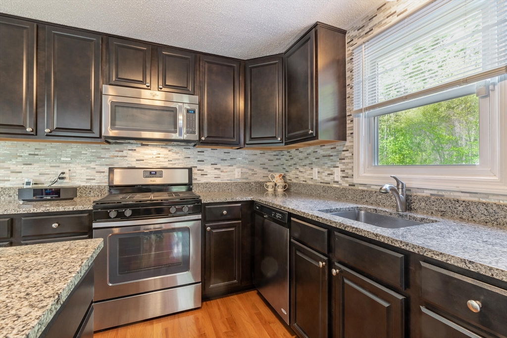 70 Parham Road Tyngsboro, MA 01879 - Photo 15 of 40 a kitchen with granite countertop wooden cabinets stainless steel appliances and a window