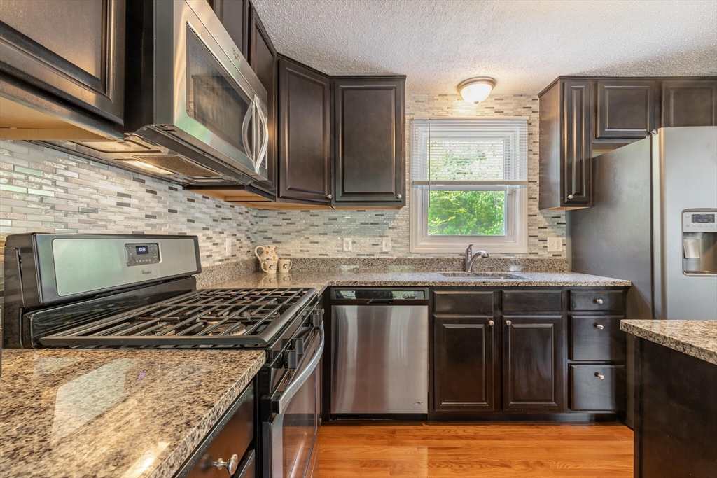 70 Parham Road Tyngsboro, MA 01879 - Photo 16 of 40 a kitchen with stainless steel appliances granite countertop a stove a sink and a microwave