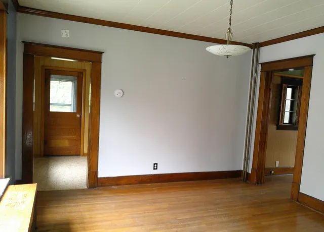 a view of an empty room with wooden floor and a window