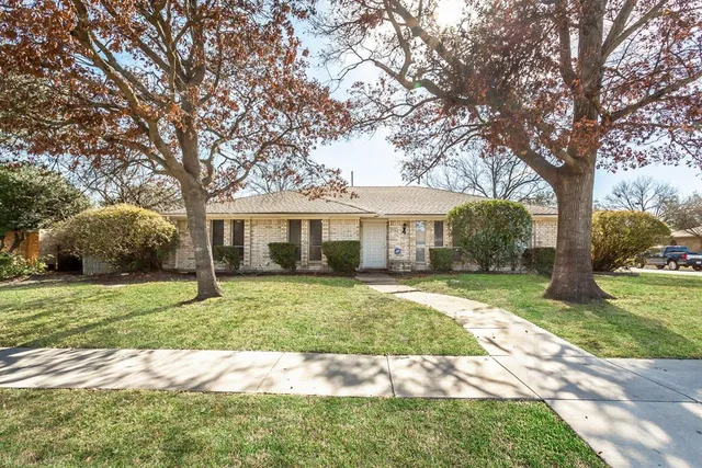 a front view of a house with a garden and trees