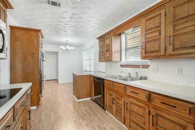 a kitchen with granite countertop a sink cabinets stainless steel appliances and a counter top space
