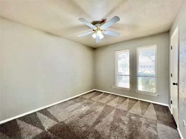 an empty room with windows and fan