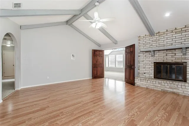 a view of an empty room with wooden floor fireplace and a window