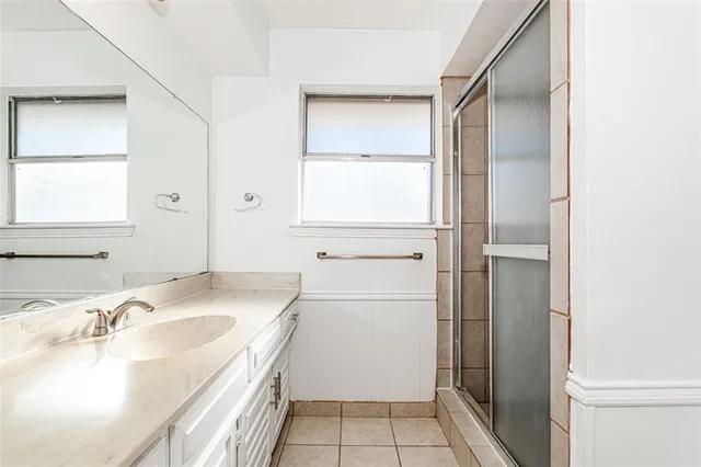 a bathroom with a granite countertop sink a mirror and a shower