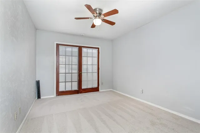 an empty room with chandelier fan and windows