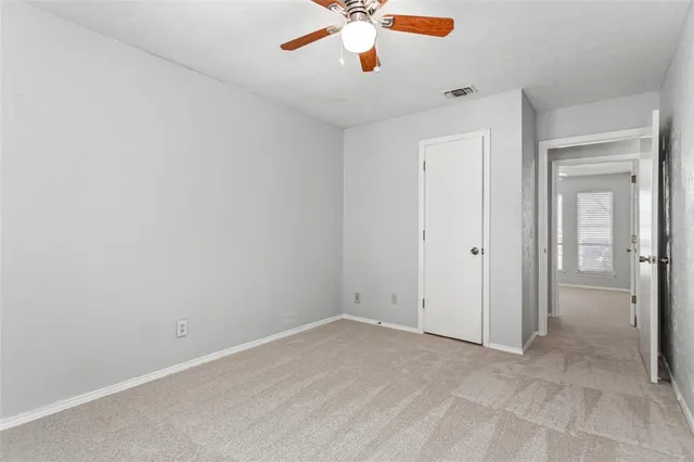 an empty room with closet and a chandelier fan