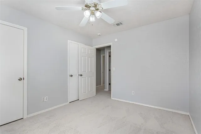 a view of an empty room with a chandelier fan