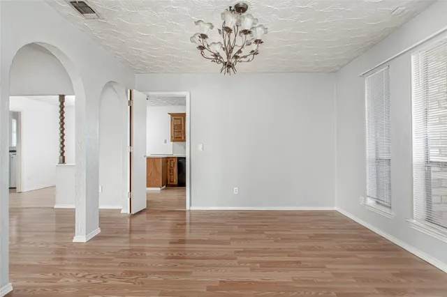 a view of a hallway with wooden floor and a chandelier
