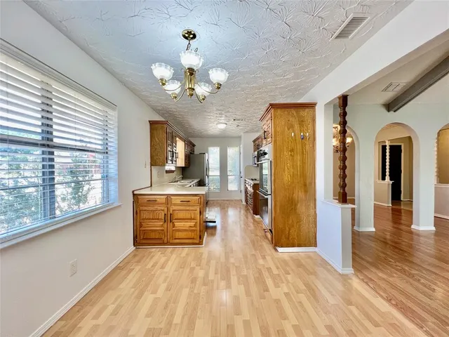 a view of a hallway with wooden floor and a kitchen
