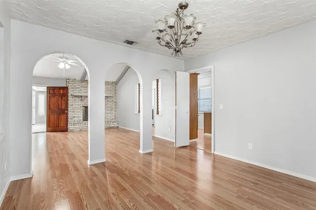 a view of a hallway with wooden floor and a chandelier