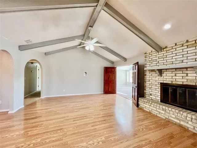 a view of an empty room with wooden floor fireplace and a window