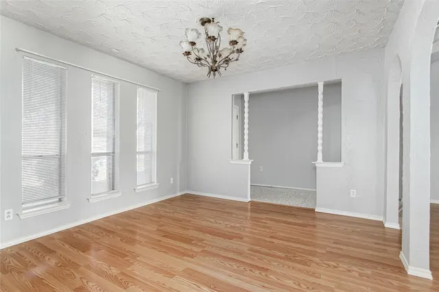 a view of a big room with wooden floor and chandelier in front of door