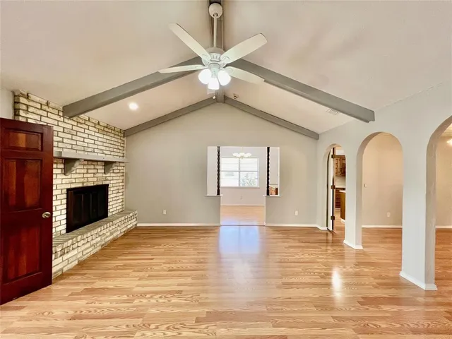 a view of an empty room with a fireplace and wooden floor