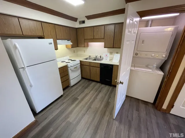 a kitchen with a refrigerator a stove top oven and wooden floor